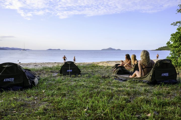 a group of people sitting around a beach next to a body of water
