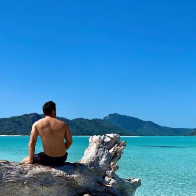 a man sitting on a rock next to a body of water