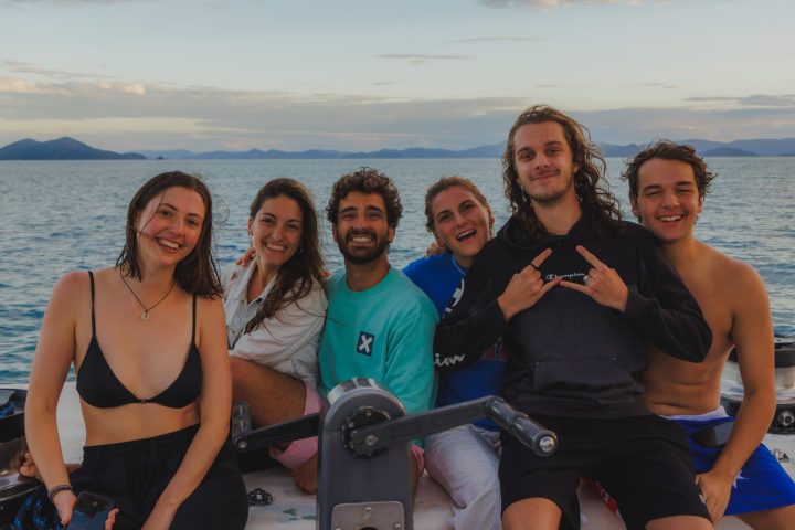 a group of people posing in front of a body of water