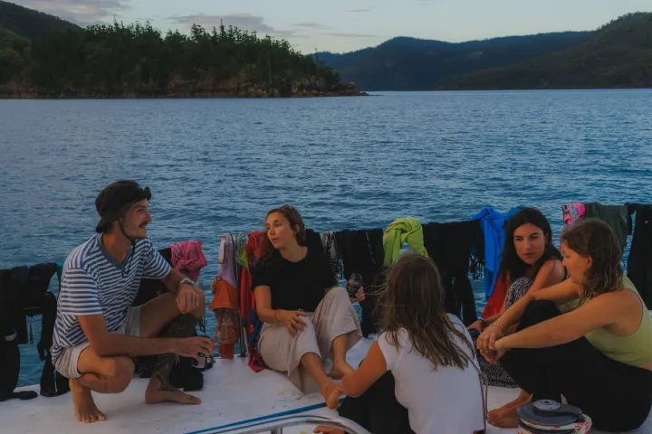 a group of people sitting in front of a body of water